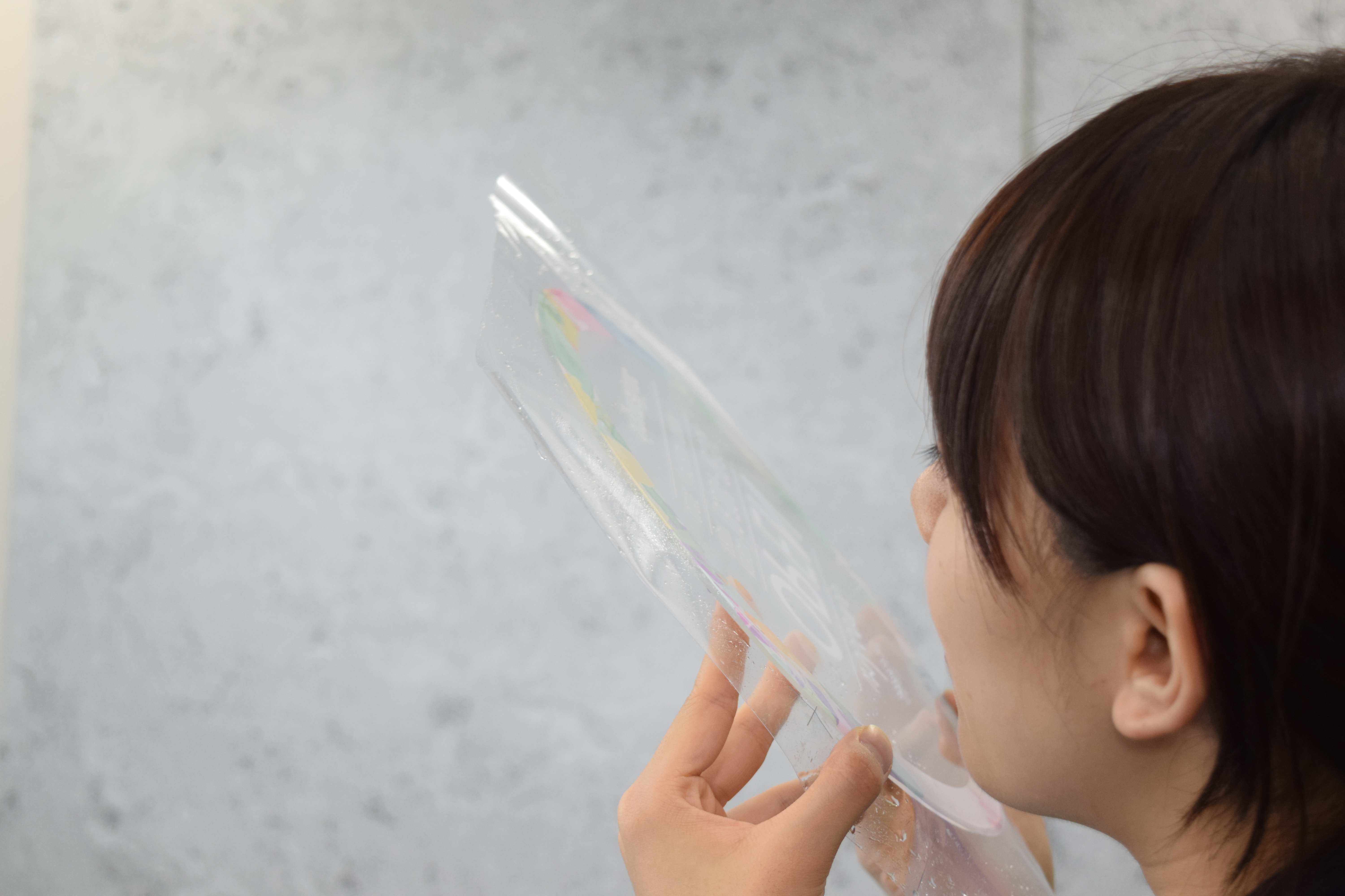 透明面板を目の高さにかざし、角度を変えながら仕上がりを見極めている様子