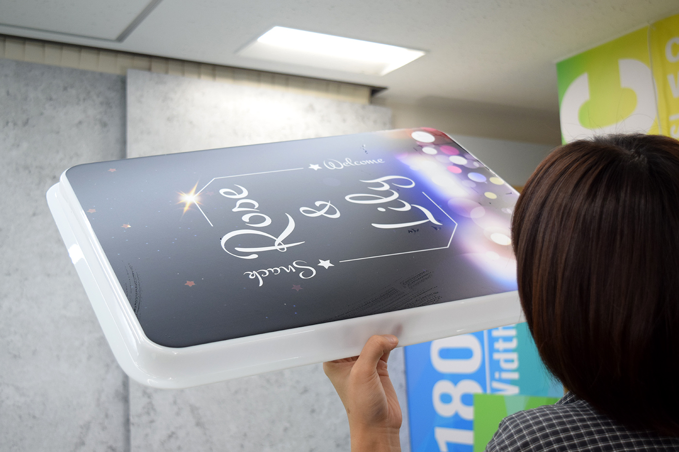 2枚目の表示面板を光に透かして検品する様子