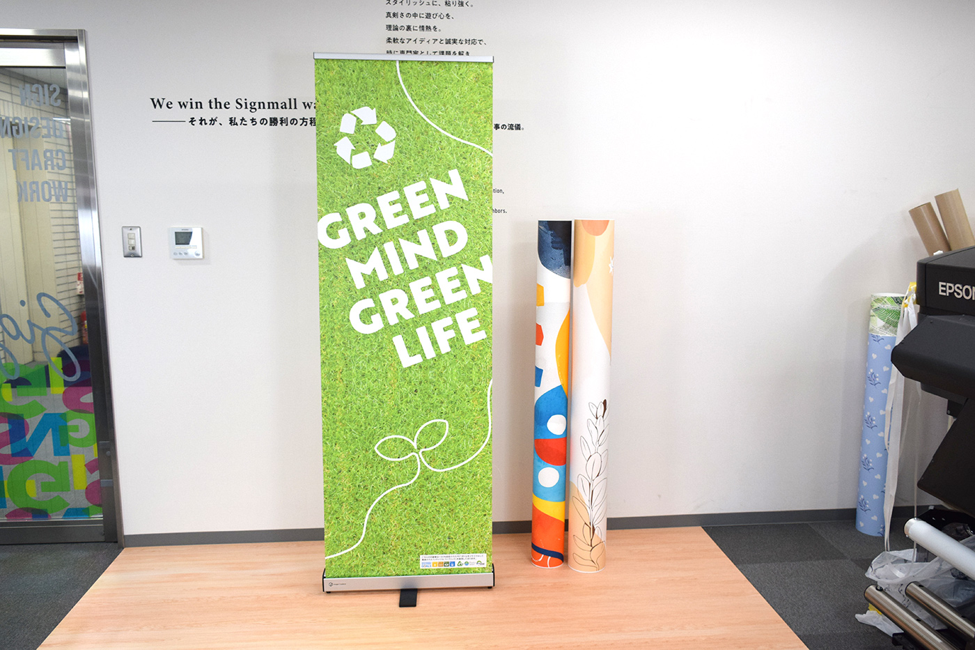 完成したPETボトルリサイクルファブリックのバナースタンド。芝生柄に「GREEN MIND GREEN LIFE」の白ヌキ文字