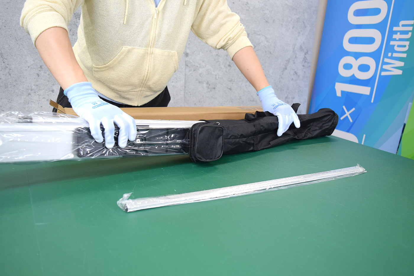 専用ケースから、ビニールで個別包装された土台器具と支柱を取り出す様子